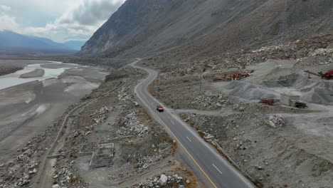 Vista-Aérea-Hacia-Atrás-De-Un-Vehículo-Que-Pasa-Por-La-Carretera-De-Gilgit-En-Pakistán-Durante-El-Día.