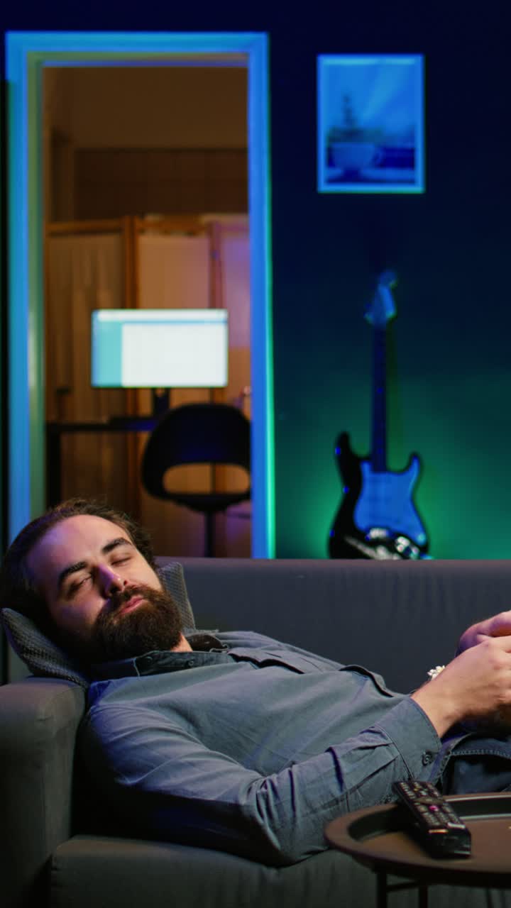 Vertical video Smiling man lounged on couch eating popcorn while watching movie