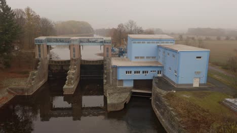 Drohnenaufnahme-Des-Kleinwasserkraftwerks-Smirice-Am-Tschechischen-Fluss-Elbe-An-Einem-Nebligen-Tag
