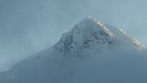 clouds slowly move across a snow covered peak in the chugach mountains alaska