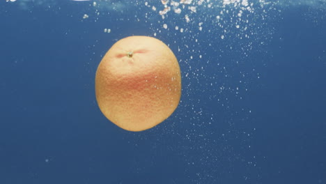 video de naranja cayendo en el agua con espacio de copia en fondo azul