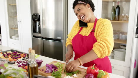 african american woman chops vegetables while on the phone