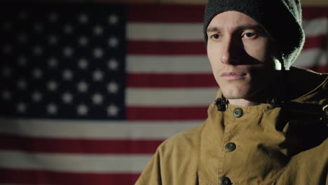 the silhouette of a man -- he looks at the american flag on the brick wall the view from behind