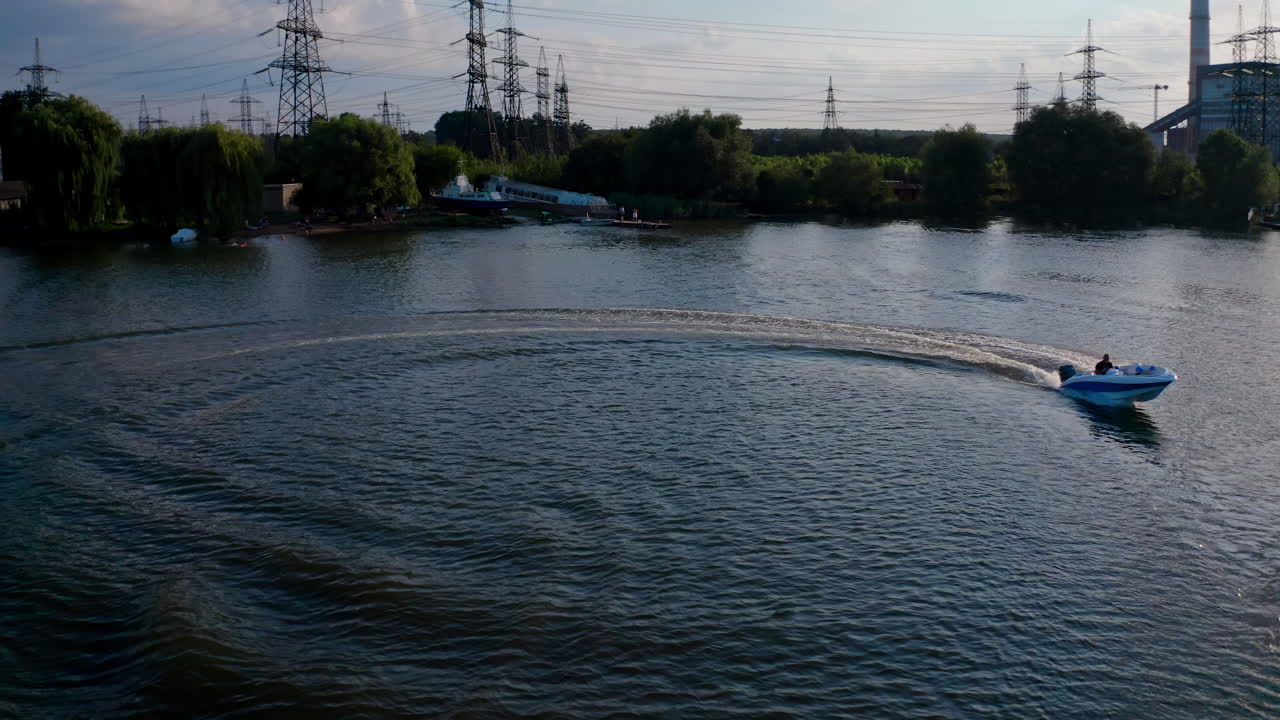 Motor boat on water at sunset. Panoramic view of the evening river with boat. Motor boat driving at the water surface and leaving a trace. View from above