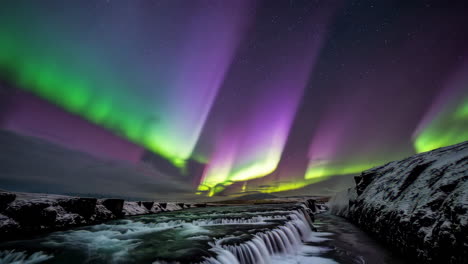 northern lights over a winter waterfall with starry sky