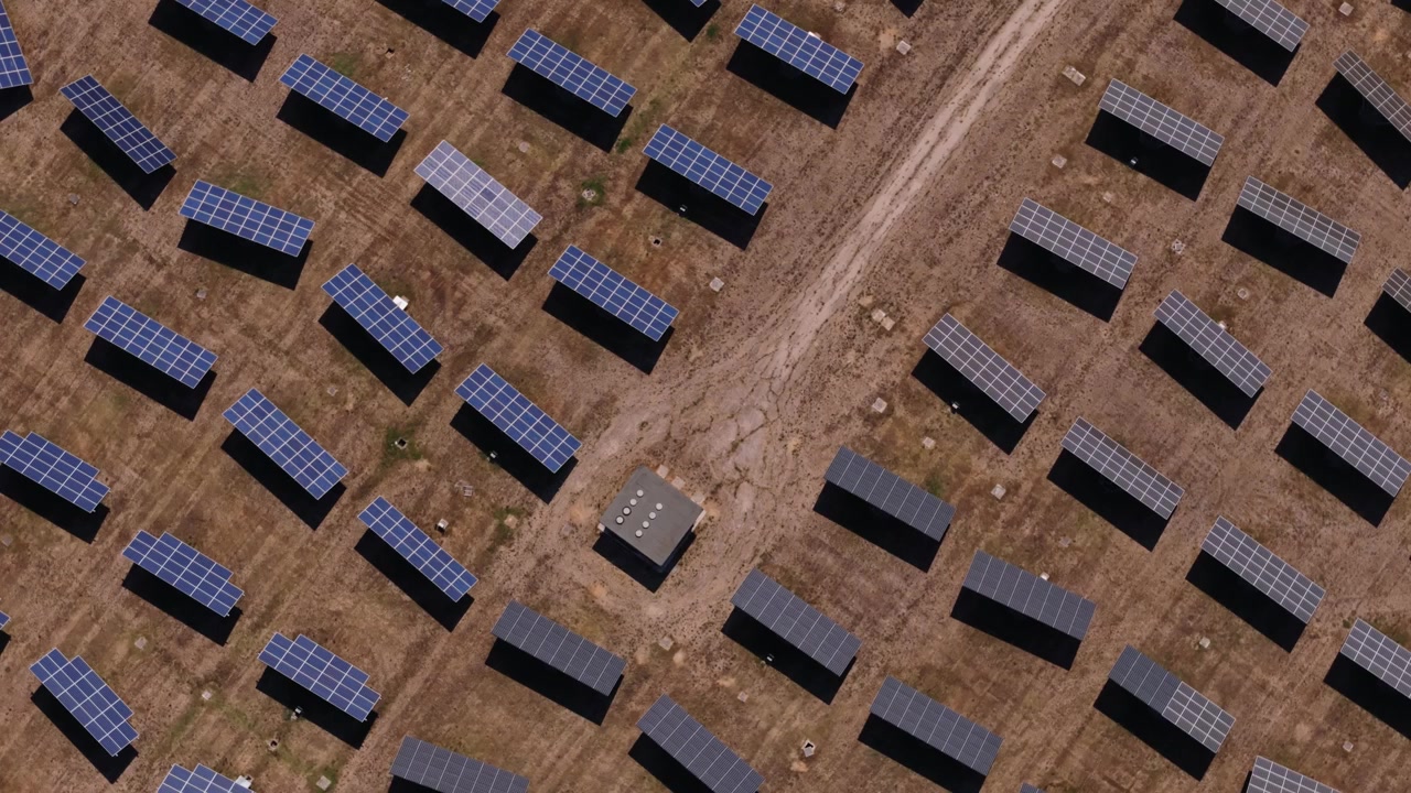 Luftperspektiv af et solkraftværk med rækker af fotovoltaiske paneler, der genererer ren, vedvarende energi på en solbeskinnet mark