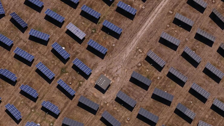 Luftperspektiv af et solkraftværk med rækker af fotovoltaiske paneler, der genererer ren, vedvarende energi på en solbeskinnet mark