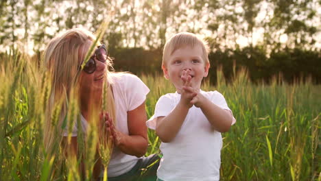 The-concept-of-a-happy-family.-Close-up-of-a-boy-and-his-mother-in-a-field-with-wheat-spikes-smiling-and-playing-with-a-soccer-ball