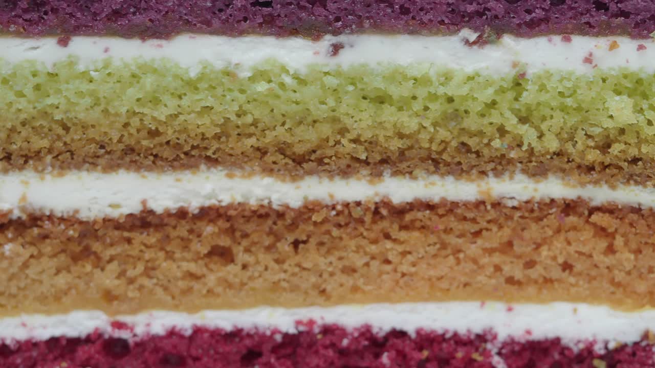 Primo piano di una torta arcobaleno colorata a strati con glassa.