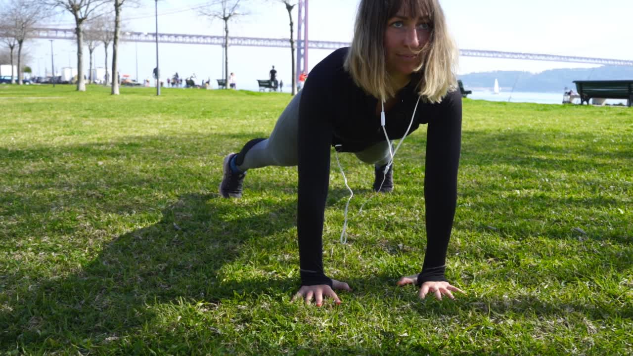chica deportiva haciendo ejercicio de tabla y estirándose en el parque