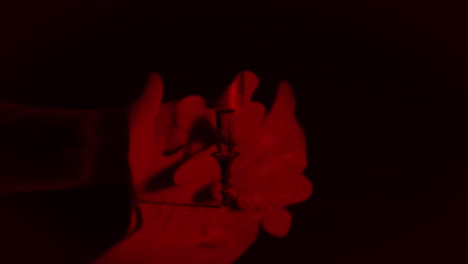 manos femeninas unidas con luz roja sobre fondo negro