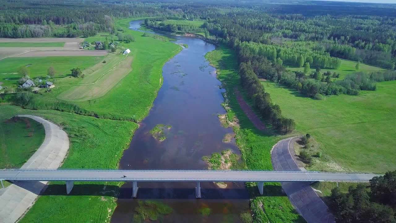 화창한 여름날 벤타 강의 공중 전망, 무성한 푸른 나무와 초원, 아름다운 시골 풍경, 흰색 콘크리트 다리 위로 앞으로 움직이는 넓은 각도의 드론 샷