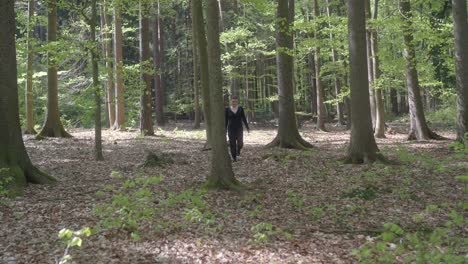 Girl-walks-through-a-forest-with-leafy-trees