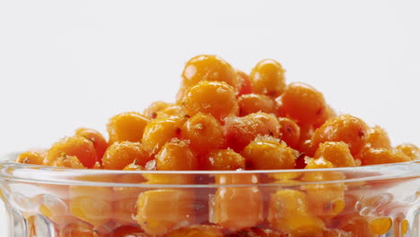 sea buckthorn healthy berries for tea drink, frozen ripe berries in glass jar and branches with leaves top view on dark wooden rustic background, great for skin, heart, vessels and immune system. copy space.