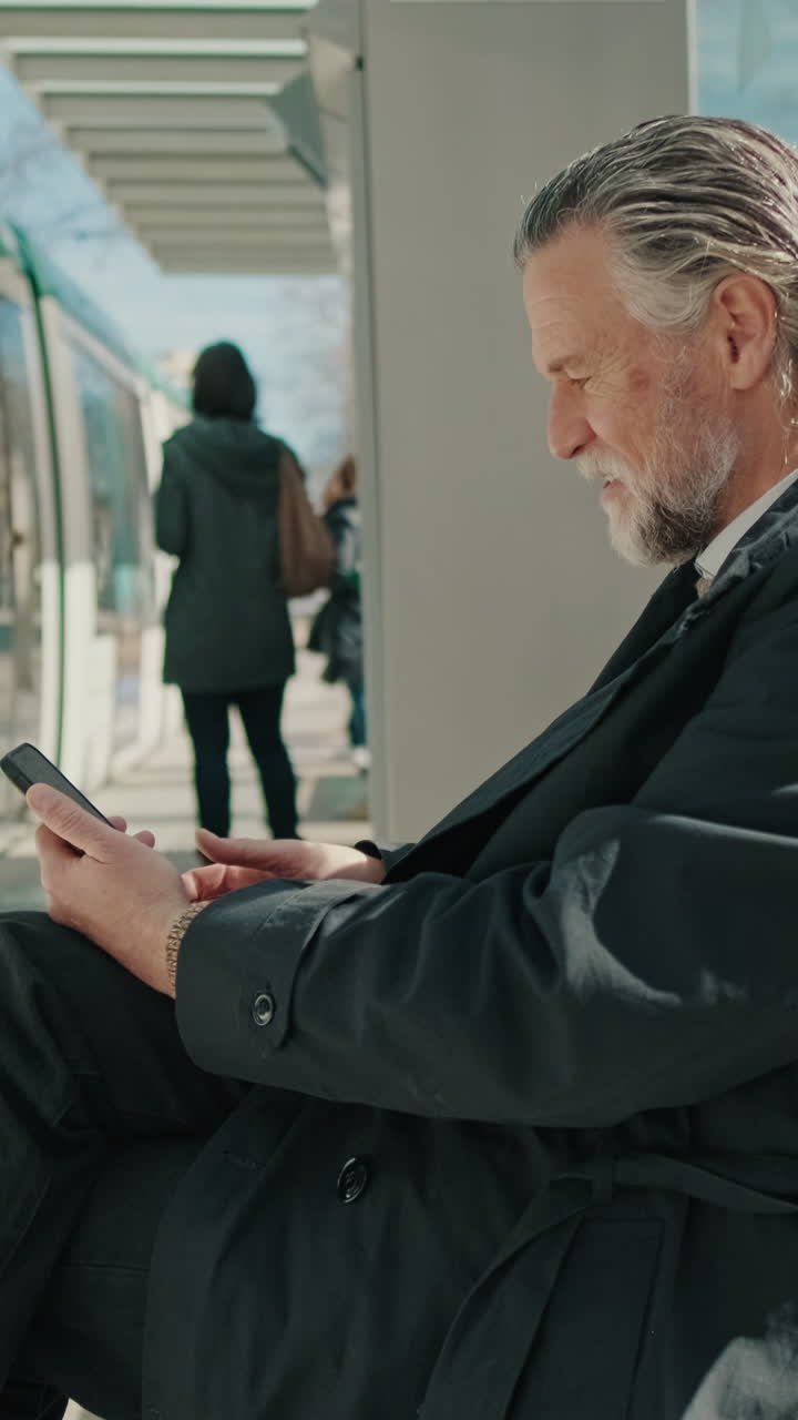 Forretningsmand der bruger telefon ved et stoppested