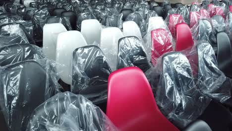 Rows-of-plastic-black,-white,-and-a-few-red-chairs