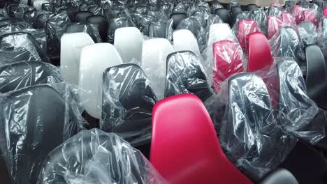 filas de sillas de plástico negras, blancas y algunas rojas