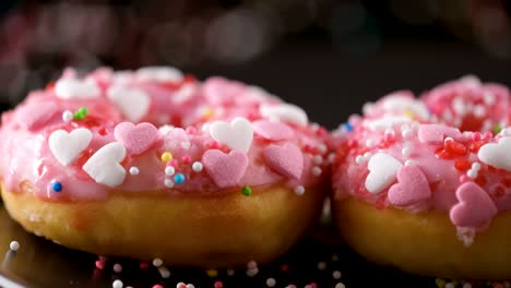 las salpicaduras que caen sobre las rosquillas rosadas con salpicadures en forma de corazón - disparo deslizante