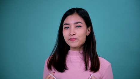 smiling asian woman wearing orthodontic retainer on blue screen background. dental care and healthy teeth.