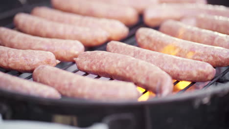 slow motion of fresh sausages grilling on fiery and smokey bbq grill