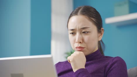 젊은 아시아 여성이 집에서 혼자 공포 영화를 보고 있습니다.