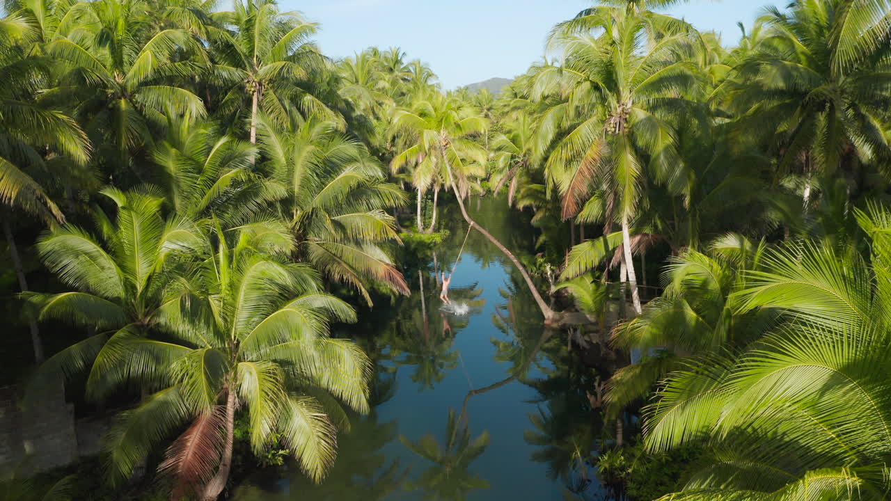 hombre saltando en el río maasin desde la isla siargao de palmeras dobladas, filipinas