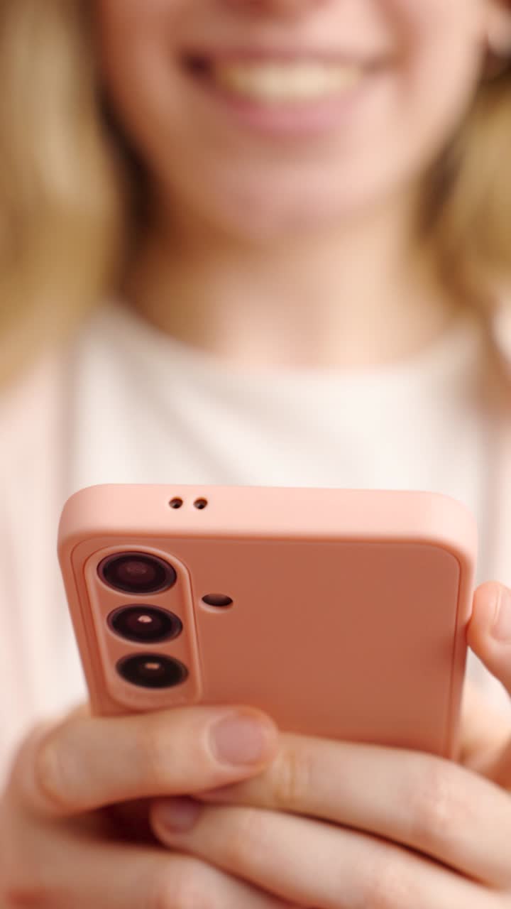 Woman smiling and holding a pink smartphone