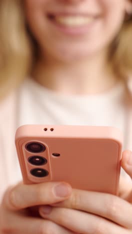 woman smiling and holding a pink smartphone