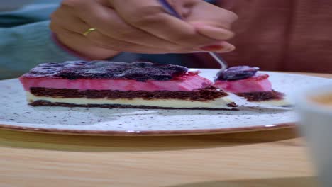 woman eating a slice of layered pink and chocolate cake