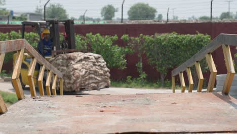 forklift driver moving a large bale of fur skins in an industrial setting