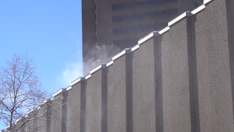 blowing snow with the effect of the wind on a building under a wintry day during winter