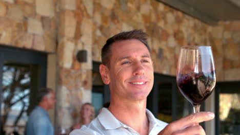 smiling man examining red wine in slow motion