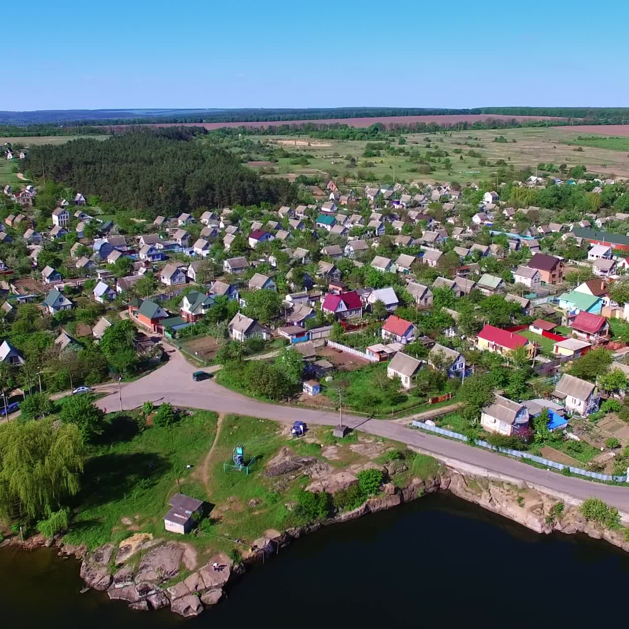 Sunny countryside landscape on a beautiful clear daytime. Lovely picturesque village locating on the bank of the river. View from top