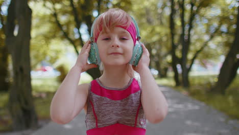 Portrait-of-athletic-sport-runner-child-girl-training,-listening-favorite-music-song-in-headphones