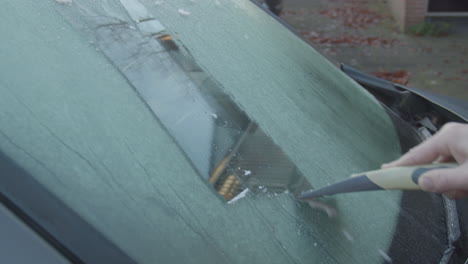 scratching ice from car window in winter