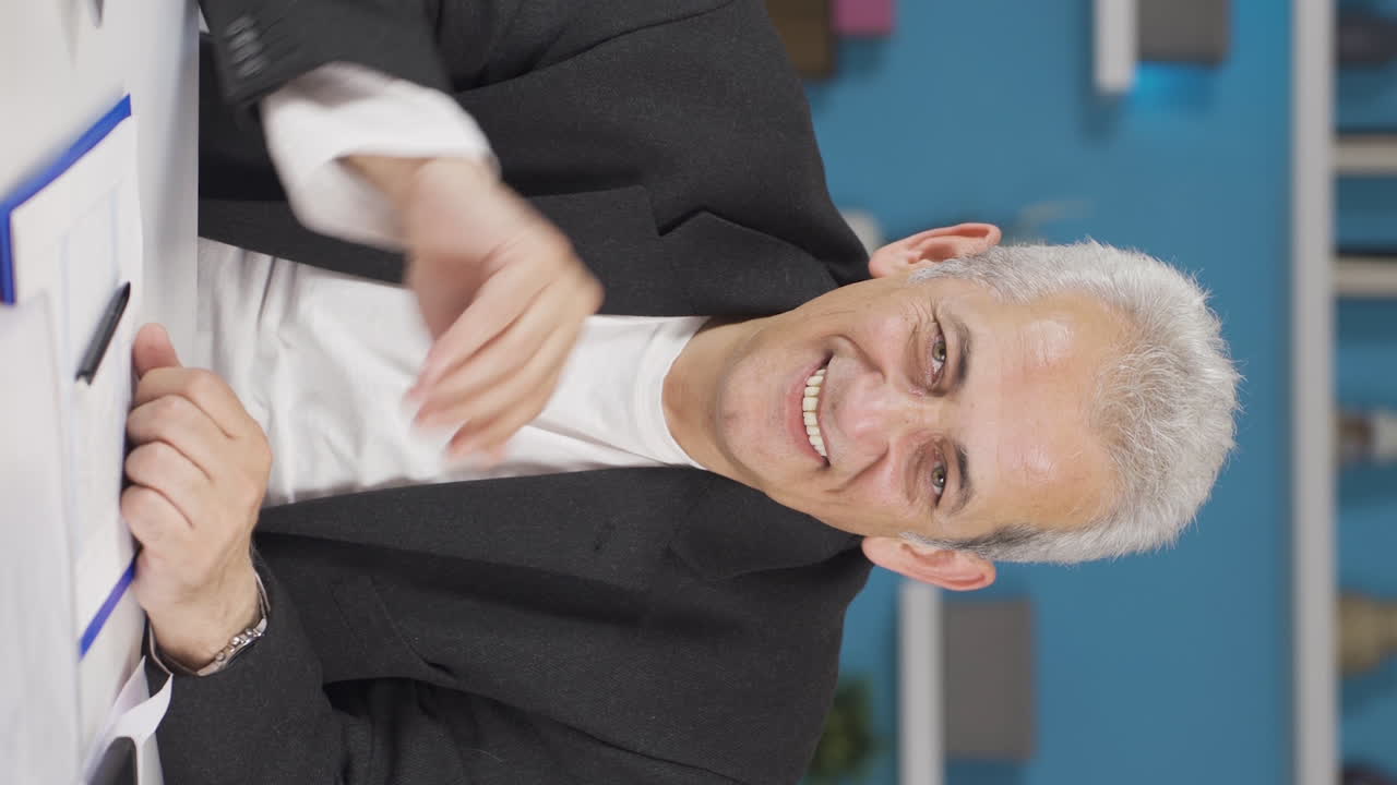 vídeo vertical de un trabajador de oficina en casa hablando en facetime mirando a la cámara.