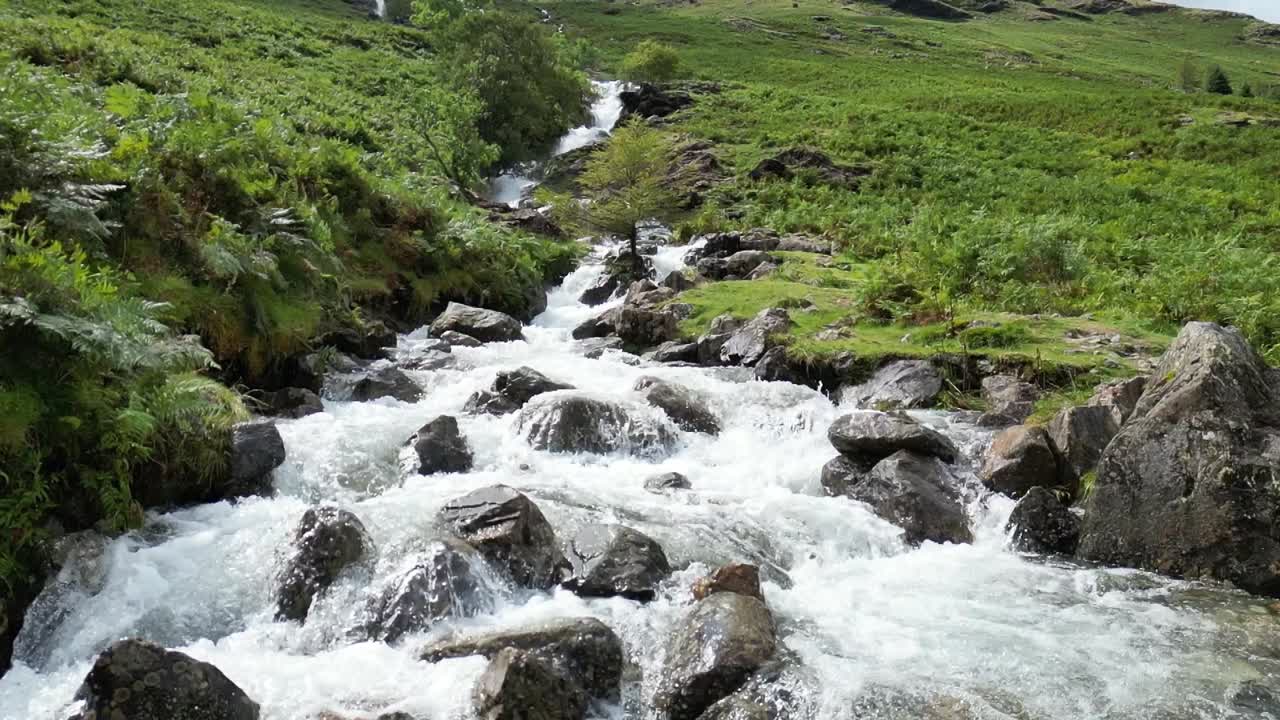 Raging waterfall cascading down mountain is slow motion after days of heavy rain, aerial drone part 2, mountain base, Buttermere, Lake District, UK