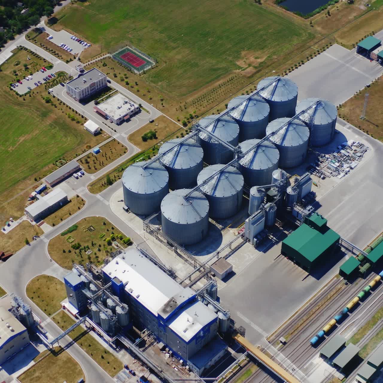 Silver silos on agro plant. Manufacturing plant for processing drying cleaning and storage of agricultural products. Flour, cereals and grain. Granary elevator. Aerial view video.