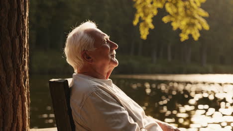 senior man relaxing by the lake at sunset