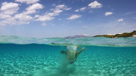 young little girl somersault back flip in clear sea water of saleccia exotic beach in corsica island, france