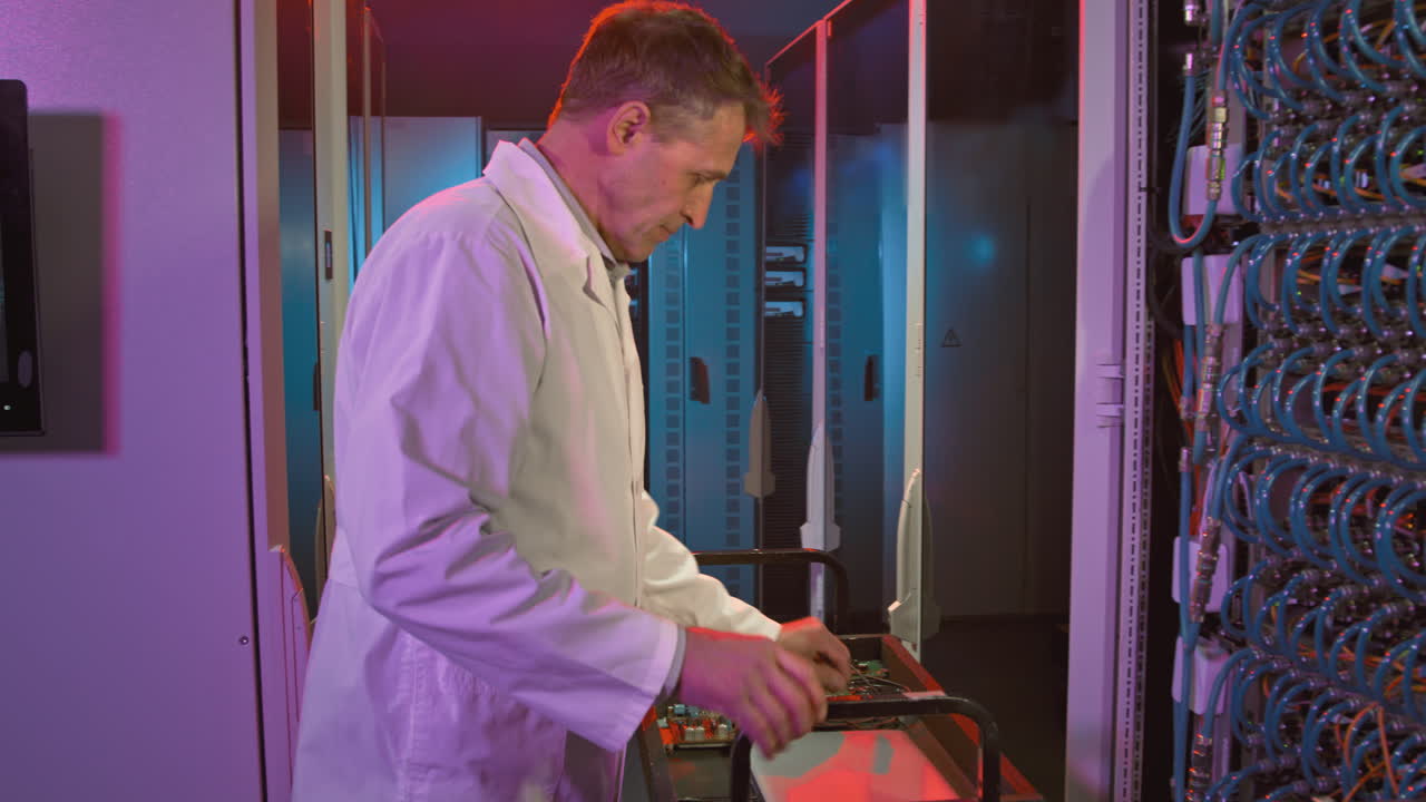 Middle-Aged Network Engineer Making Repairs in Data Center