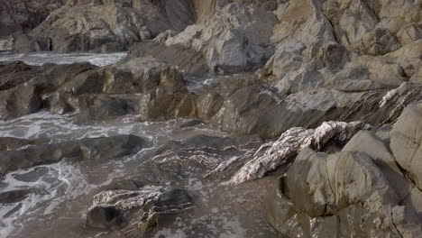 close up of waves breaking at a rocky beach during sunset in slow motion