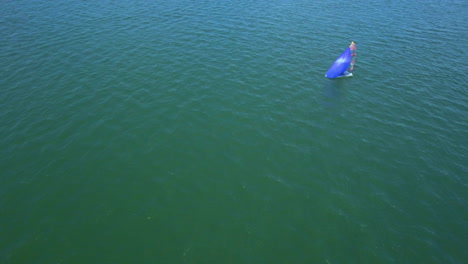 aerial: segelboot im blauen meer. ein segelboot kann am horizont gesehen werden. drone view of a single sailboat off the sea. white sailing yacht in the middle of the boundless ocean. aerial view