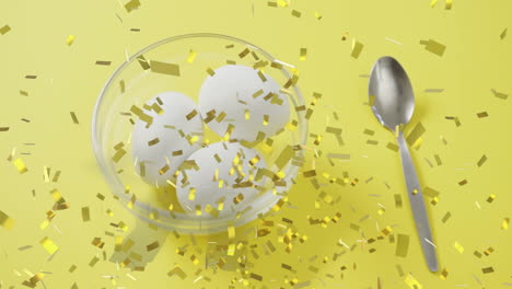 three eggs in glass bowl with spoon, surrounded by golden confetti animation