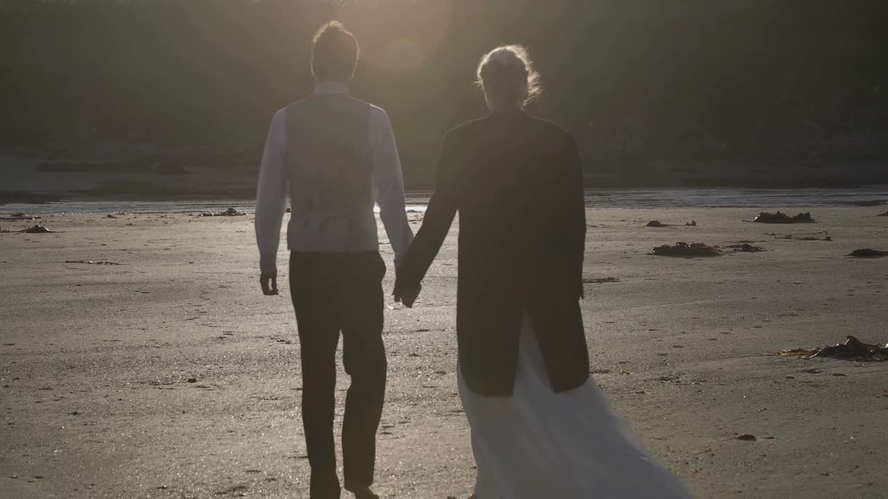 Smiling newlyweds walking together on the beach