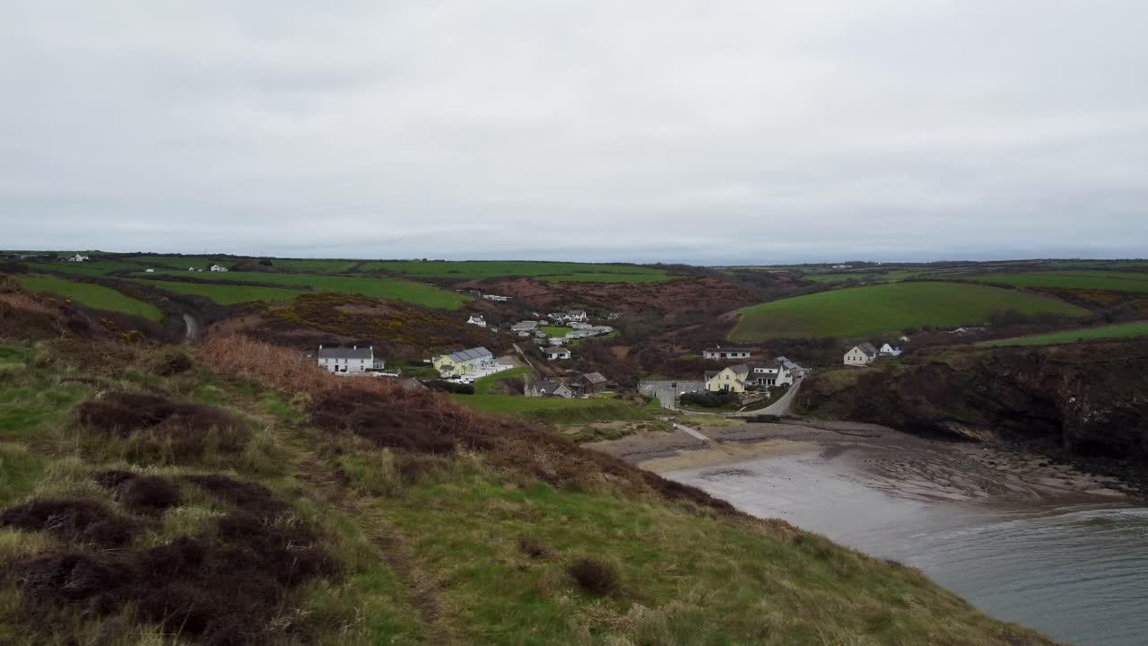 el dron aéreo lateral revela la playa de nolton haven con chalets y caminos rurales y campos de campo ondulados reino unido 4k