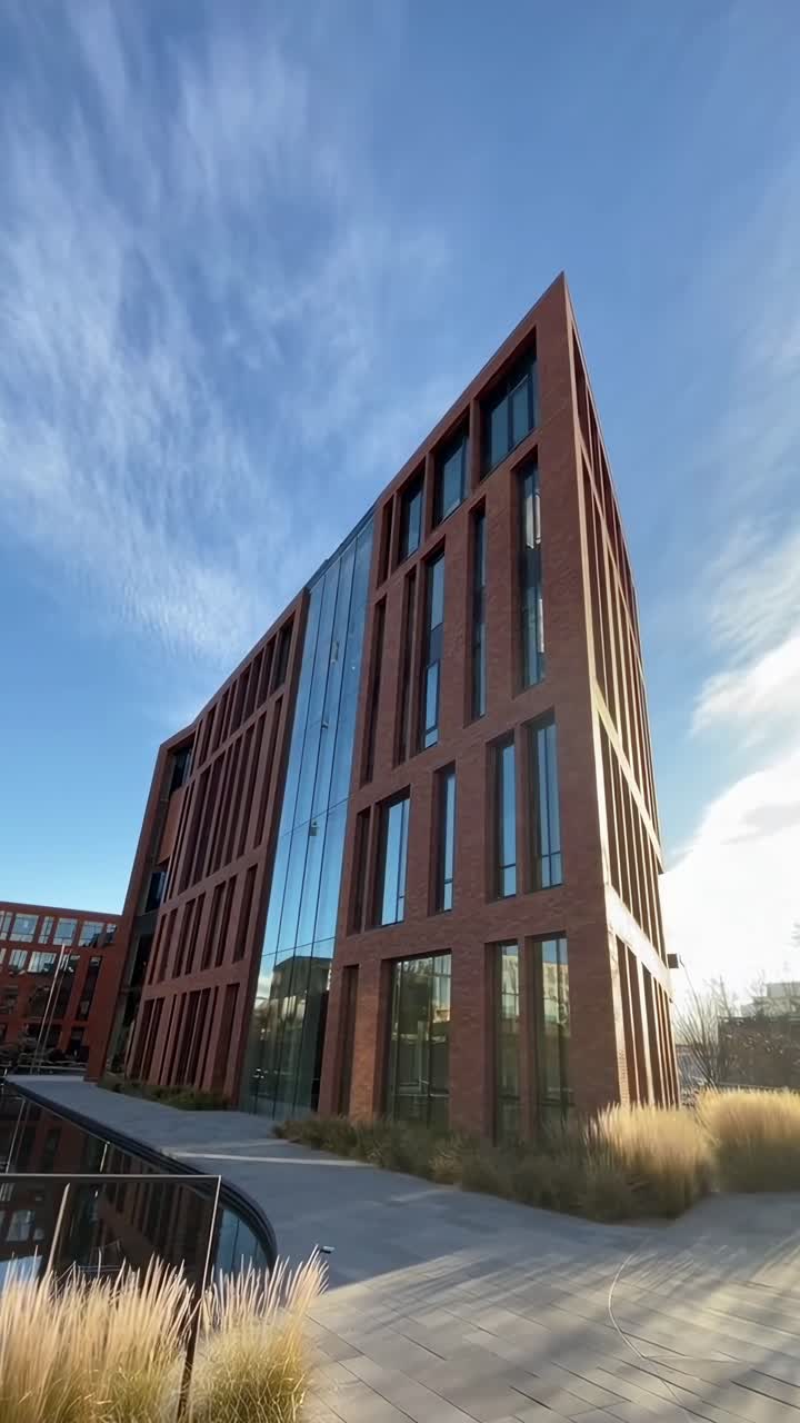 Video da angolazione bassa di un edificio moderno e angolare con facciata in vetro su un cielo blu