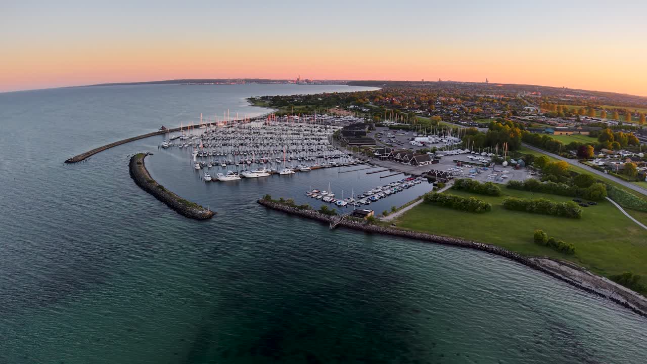Vista aerea al tramonto di Egå Marina con banchine, barche a vela e costa lungo la costa danese