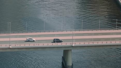 Aerial-View-Of-Car-traffic-Moving-On-Bridge-Above-River
