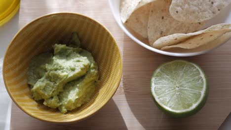 fresh guacamole with tortilla chips and lime slice ready to enjoy